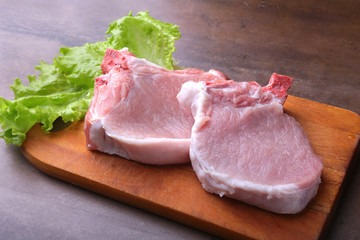 Raw chop on a rustic cutting board with salt, pepper and grinder for spices . for copy space. Top View.