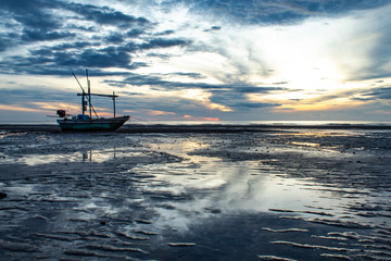 The morning sun light in the sea, and the boat on the beach.