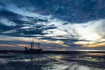 The morning sun light in the sea, and the boat on the beach.