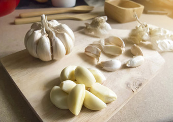 Close Up Garlic Bulb and Garlic Cloves on Wooden chopping board placed on the MDF wooden plate board Texture Background.