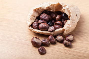 Chestnuts in a paper bag on a light wooden table