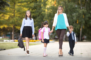 Children siblings and Mother holding hands going to school