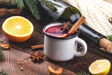 Mulled wine, a bottle of red wine, spruce branches, cinnamon, anise tree, orange and lemon on a wooden background. A cozy, winter evening. Winter drinks. Christmas Eve