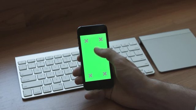 Using mobile phone with green screen laying on a table with keyboard