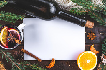 Mug of hot mulled wine with spices, citrus fruits, cinnamon and anise stars on a wooden background....