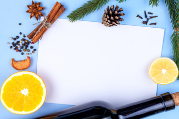 Ingredients for mulled wine. Bottle of red wine, lemon, anisetree, spices, cinnamon, orange on a blue background. Copy space, top view. Flat lay. Winter drinks