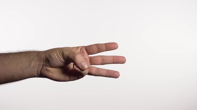 Hand goes into frame in a fist and opens hand to show all three fingers