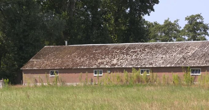 old barn with asbestos roof in Dutch countryside. In Holland it will be prohibited by law to have any roofs with traces of asbestos in them by 2024.