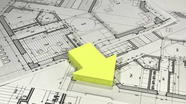 Blueprints - architectural drawings and house symbol from a pack of yellow stickers smoothly rotate on the surface of the architectural drawings