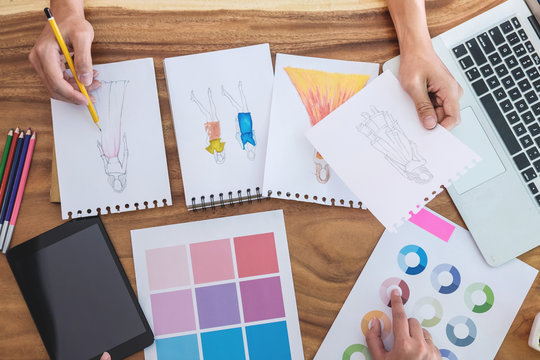Two young professional Fashion designer colleagues working and project of drawing sketches for clothes in workplace with laptop, digital tablet and color charts, Fashion Designer Stylish Concept