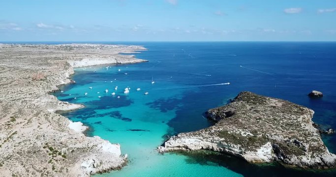 Aerial view of Isola dei Conigli next to the island of Lampedusa, Sicily, Italy with Mediterranean sea. Italian summer landscape seen from the sky with drone flying over beach