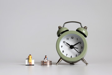 An alarm clock and miniature women. The concept of women's time and economic poverty.