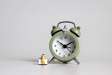 An alarm clock and miniature women. The concept of women and time poverty.