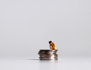 A pile of coins and a miniature woman. The concept of women's economic problems.