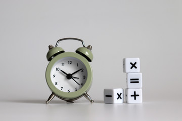 White arithmetic symbols cube and an alarm clock.