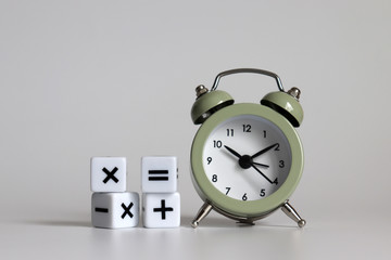 White arithmetic symbols cube and an alarm clock.