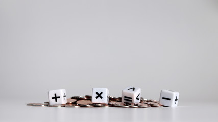 White cubes with arithmetic symbols and pile of coins.
