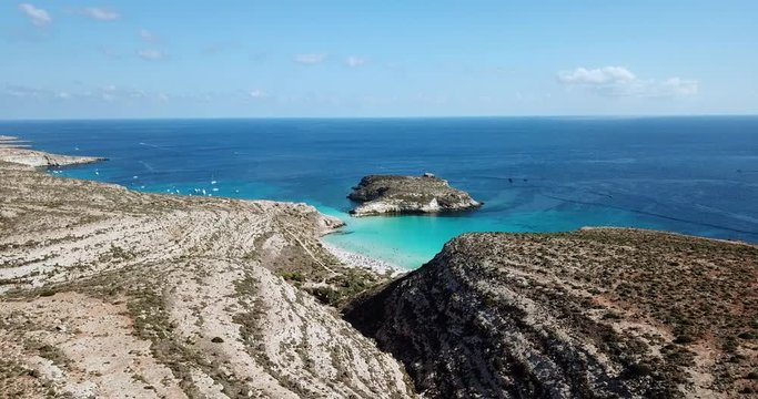 Aerial view of Isola dei Conigli next to the island of Lampedusa, Sicily, Italy with Mediterranean sea. Italian summer landscape seen from the sky with drone flying over beach