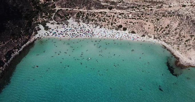 Aerial view of the island of Lampedusa, Sicily, Italy near Isola dei Conigli with Mediterranean sea. Italian beach with people swimming on holiday as seen from the sky with drone flying