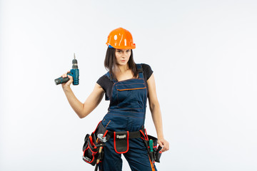 Young woman with toolbelt using driil and some power tools for her work at home. Girl working at...