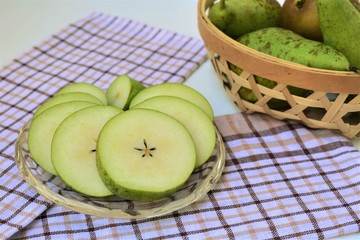 Ripe green pear sliced, on a glass plate, sweet organic dessert. 