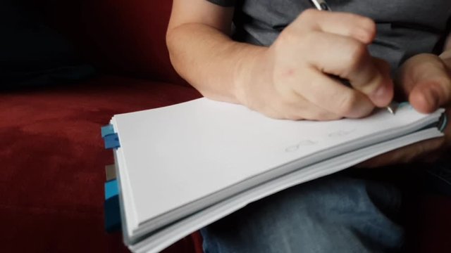 Male with a partially amputated index finger on his right hand sat down holding a pen and pad  writing a to do list.