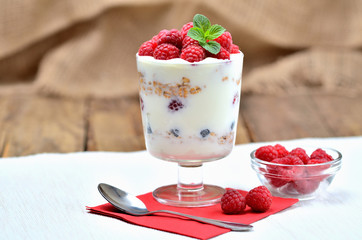 Homemade yoghurt with oatmeal and fresh raspberries in a glass