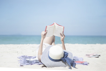 A portrait of beautiful asian woman holding red book in hand. Happy classic man on white sand at Andaman Sea with beautiful blue sky and clear water. Concept summer vacation holiday.