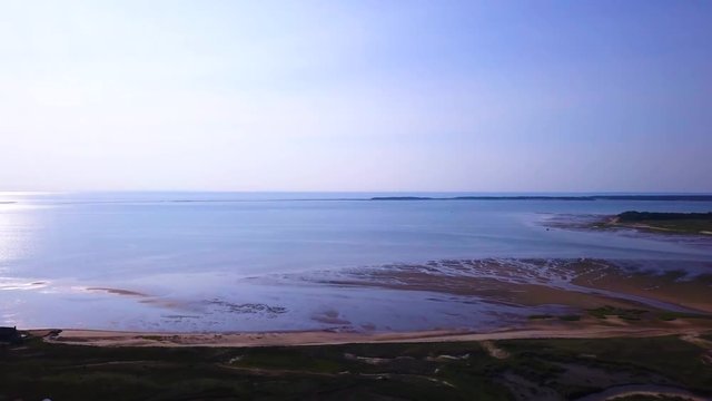 Sunken Meadows on Cape Cod, MA. A wide shot shows how vast the size of the bay can be. The tide is low and much of the beach is freshly exposed. The camera pans to the right as it descends.