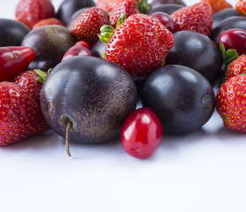 Various fresh summer fruits. Ripe strawberries and plums on white background. Fresh fruits at border of image with copy space for text. Background fruits.