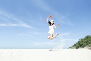 A portrait of happy asian girl jumping and holding bunch of colorful air balloons at the beach, good vacation in summer , Phuket ,Thailand