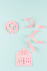 Halloween concept origami cartoon art - pink terrible house with bats fly and spooky moon on trendy pastel mint blue background.