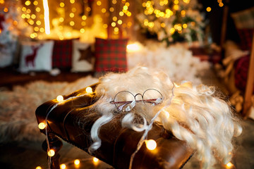 Concept of Christmas and New Year. Beard and sunglasses of Santa Claus on a chair in the doe for Christmas.