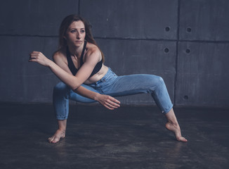 young beautiful woman in top and jeans dancing modern contemporary dance in the studio, contemporary art, harmony of body and soul, professional dancer