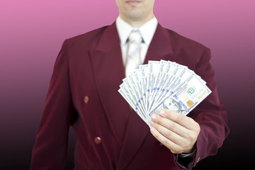 Man in a business suit holds a fan of hundred-dollar bills