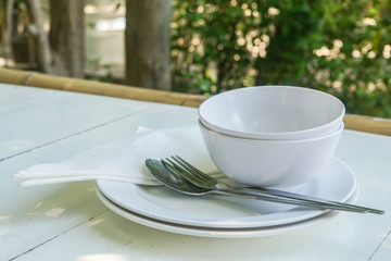 white plastic dish and bowl with cutlery on  outdoor wooden table