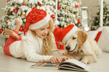 Girl with golden retriever are reading book, christmas