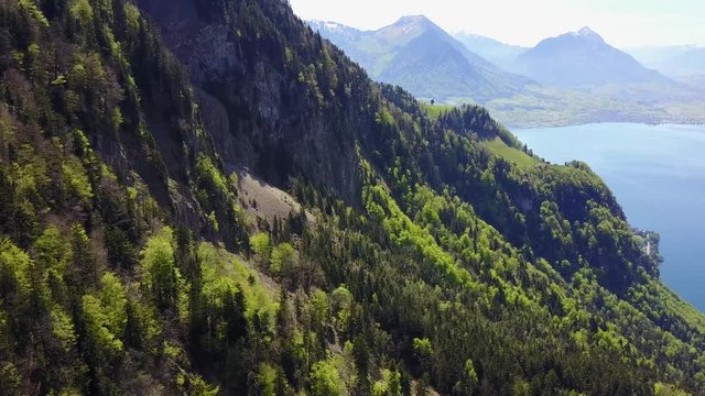 Aerial footage of massive snowcapped mountains surrounded by clear turquoise lakes and small villages.