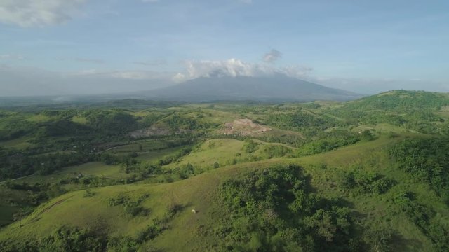 Aerial view of mountain valley with hills covered forest, trees, mount Iriga. Luzon, Philippines. Slopes of mountains with evergreen vegetation. Mountainous tropical landscape.