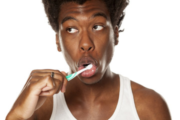 portrait of a happy young dark-anm brushing his teeth with black toothpaste on a white background
