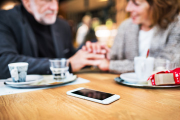 Senior couple with a smartphone in a cafe. Christmas time.