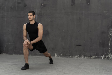 Handsome, athletic man warming up stretching before the training