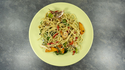 Spaghetti seafood in a green plate on a black stone floor table, Top view with copy space for your text..