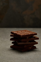 close-up view of sweet tasty stacked chocolate bars on grey background