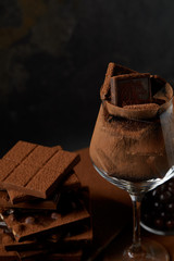 close-up view of glass and delicious assorted chocolate pieces on black