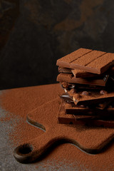 close-up view of tasty chocolate bars with cocoa powder on chopping board