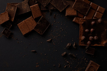 top view of assorted delicious chocolate pieces on black background