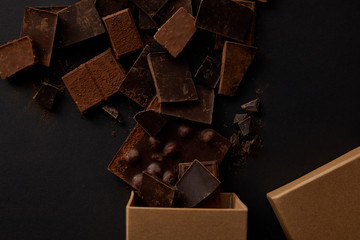 top view of box and assorted delicious chocolate pieces on black