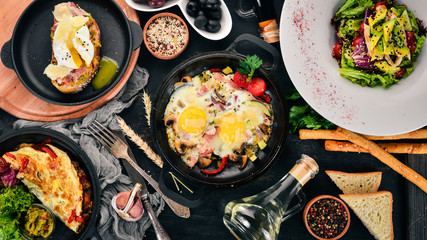 A set of food. Shakshuka, omelette, avocado salad, sandwich with poached egg. On a wooden background. Free space for text. Top view.