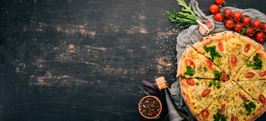 Pizza with cherry tomatoes, suluguni cheese and basil. Italian cuisine. On a wooden background....